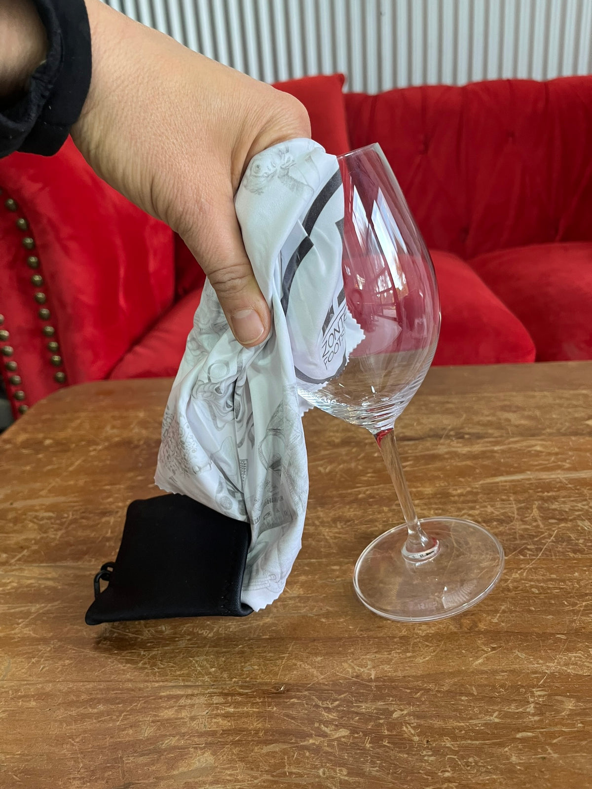 A hand polishing a wine glass with a white microfibre cloth